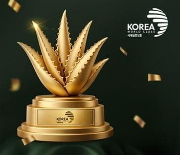 받침에 KOREA 세계일류상품 표시가 새겨진 금색 알로에 트로피와 흩날리는 금박, 오른쪽 위에 KOREA WORLD CLASS 세계일류상품 마크