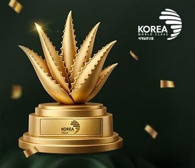받침에 KOREA 세계일류상품 표시가 새겨진 금색 알로에 트로피와 흩날리는 금박, 오른쪽 위에 KOREA WORLD CLASS 세계일류상품 마크