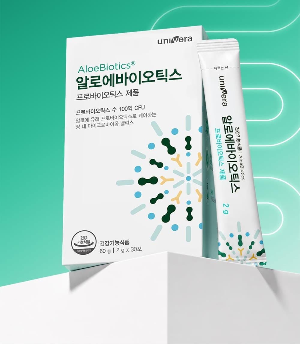초록 그라데이션 지면 위 흰 단에 놓인 알로에바이오틱스 상자와 스틱 1포. 상자 글자: univera, AloeBiotics®, 알로에바이오틱스, 프로바이오틱스 제품, 프로바이오틱스 수 100억 CFU, 알로에 유래 프로바이오틱스로 케어하는 장 내 마이크로바이옴 밸런스, 건강기능식품 60 g | 2 g x 30포