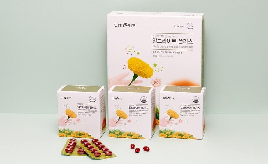 연녹회 벽 앞 알브라이트 플러스 큰 상자(건강기능식품 | Albright Plus · EPA 및 DHA 함유 유지 · 루테인 · 비타민A 제품 · 216 g)와 작은 상자 셋, 빨간 캡슐 블리스터 둘과 캡슐 셋