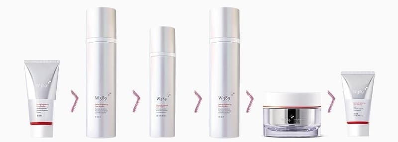 W389 제품 여섯이 차례로 놓인 줄 — 필링젤 튜브, 토너 병, 스팟 에센스 병, 로션 병, 크림 단지, 선크림 튜브(은빛 · 빨간 띠). 사이사이 연자주 꺾쇠