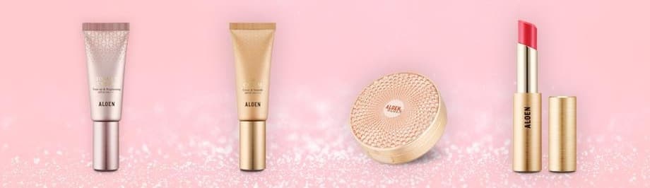 분홍 반짝이 지면 위의 알로엔 메이크업 4종 — 톤업크림(분홍 튜브), 비비크림(금색 튜브), 스킨커버(금빛 쿠션), 립세럼스틱(분홍 립스틱과 금색 뚜껑)